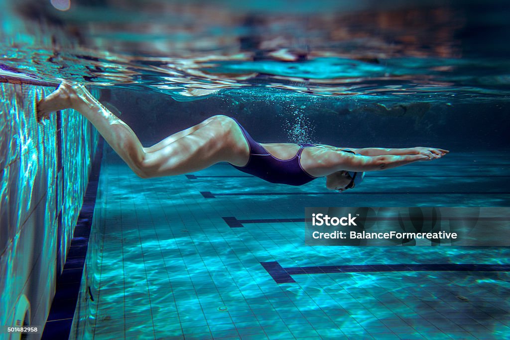 Female swimmer at the swimming pool. Female swimmer at the swimming pool.Underwater photo.Grain added. Swimming Stock Photo