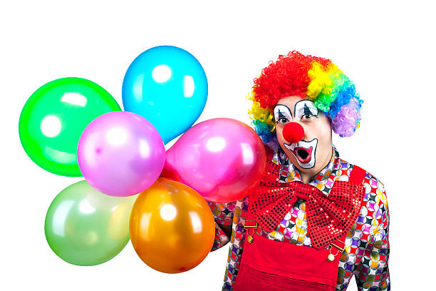 Clown Makes Funny Face Portrait of colorful birthday clown making a funny face with balloons isolated on white. circus clown carnival harlequin stock pictures, royalty-free photos & images
