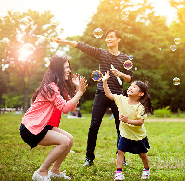 ご家族での楽しい公園、石鹸の泡 - bubble wand child blowing asian ethnicity ストックフォトと画像