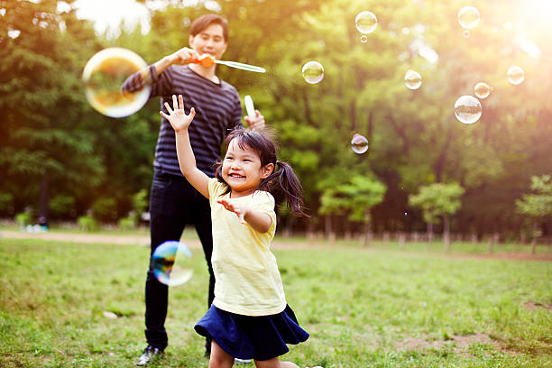 padre e hija divirtiéndose en el parque con las burbujas de jabón - japonés oriental fotografías e imágenes de stock