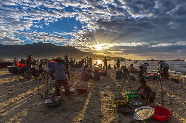 Market early in fishing village Danang Da Nang, Vietnam, June 26, 2015: Market early in fishing village Danang when people busy buying and selling fish, transport fish to markets when sun rays radiating prepared to make the atmosphere very lively, all because of the living of life in the region Danang, Vietnam basket boat stock pictures, royalty-free photos & images