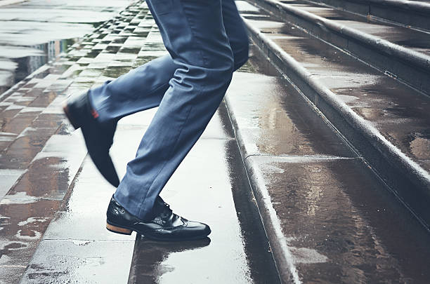 istock Man in suit running late up steps in rain 501491976