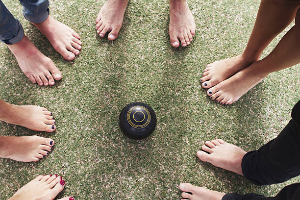 Overhead view of bare feet friends around lawn bowls stock photo