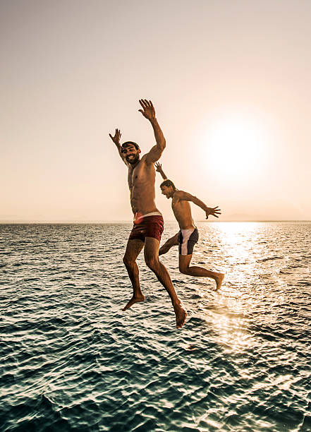 istock Playful men having fun while jumping into the sea. 501509750