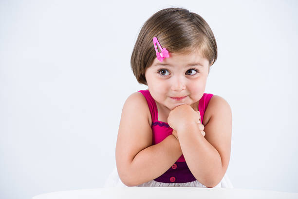 rear view of little girl wearing pink smart casual dress cloth holding head. long hair elementary school age children
