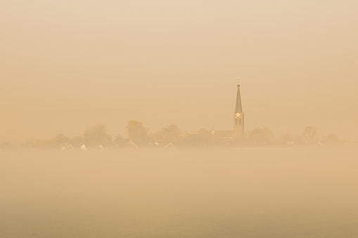A typical dutch village in the foggy golden morning light.