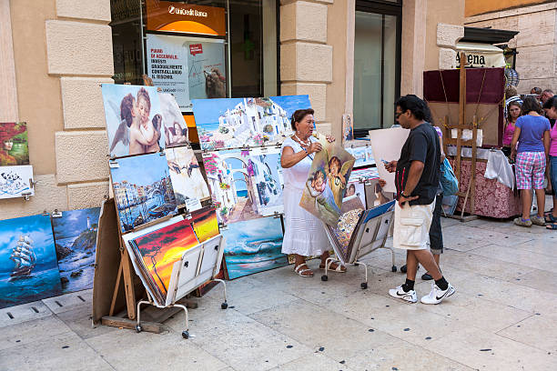 Verona, Italy - August 5, 2009: people enjoy walking at Piazza Bra in Verona. Local people offer paintings to tourists. This place was in roman times a meadow , the Pratum.
