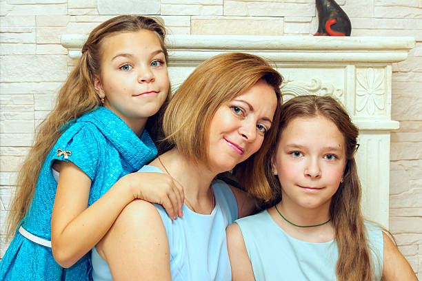 istock Mother and her two daughters sitting near the fireplace. 501513126