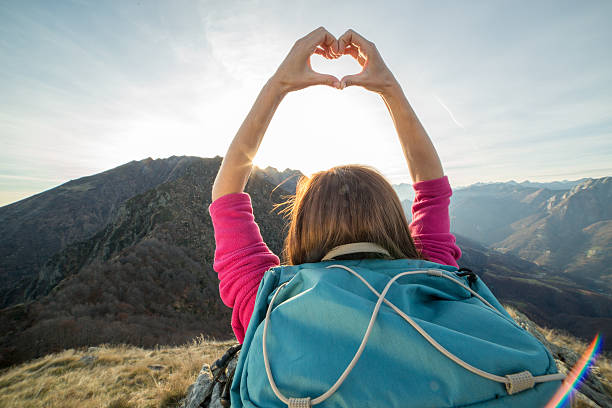 istock Young woman on mountain top makes heart shape finger frame 501513172