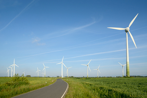 Road along the Wind Turbine Farm. Low-angle view, taken in Ostfriesland, Lower Saxony, Germany, Europe.