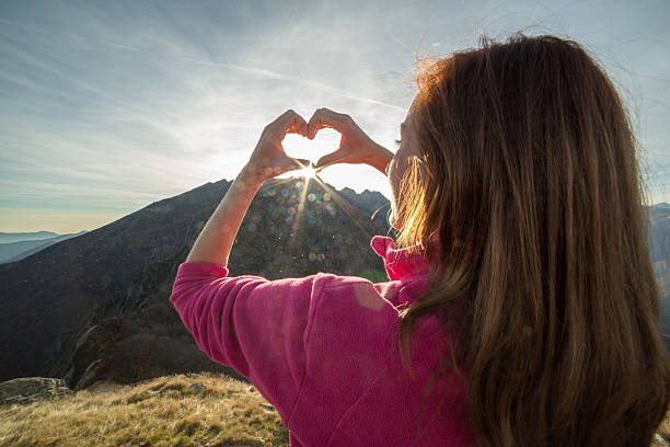 istock Young woman on mountain top makes heart shape finger frame 501516364