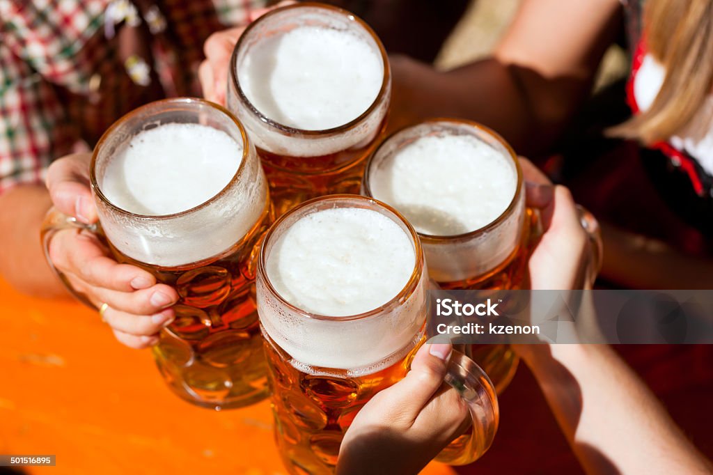 Bavarian party Four friends with a fresh beer in a Beer garden, close-up on beer stein Beer Stein Stock Photo