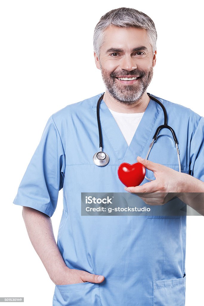 Cardiology surgeon. Confident mature cardiology surgeon holding heart shape toy and smiling while standing isolated on white Adult Stock Photo