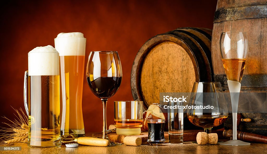 alcoholic drinks alcoholic drinks on wooden table in glasses, mugs and shots with barrel in background Wine Stock Photo