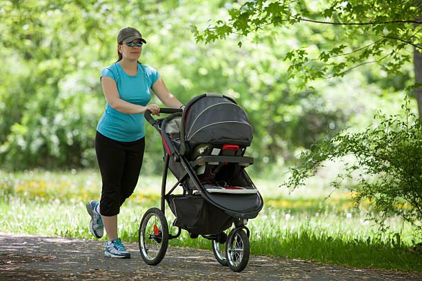 Young woman with a stroller Young mother running while pushing a stroller in the park pushchair stock pictures, royalty-free photos & images