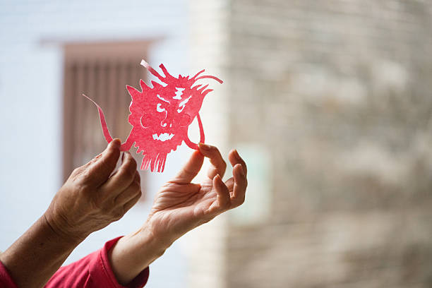A bright and colourful inflatable kite with large eyes and flowing tentacles flying against a clear blue sky during a kite festival.