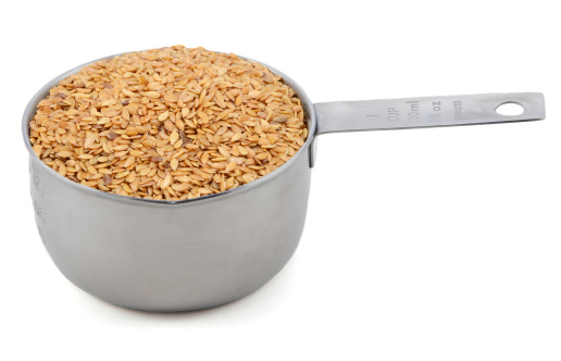 Golden linseed in an American cup measure, isolated on a white background