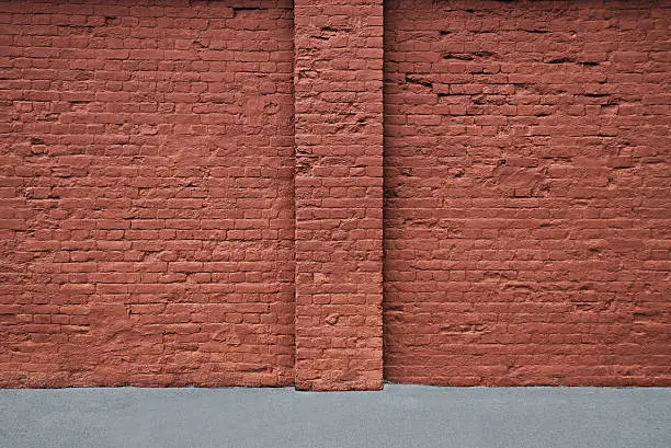 Red brick wall with the strip of asphalt and vertical column. Horisontal.