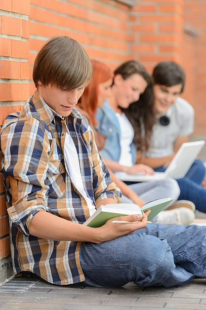 istock Young man studying book friends in background 501536821