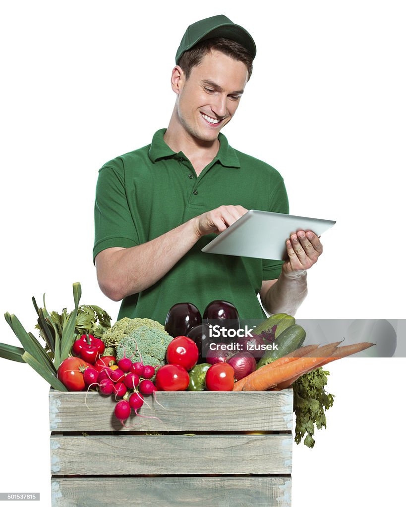 Delivery man Delivery man delivering box with organic food, using digital tablet. Studio shot, white background. Supermarket Stock Photo