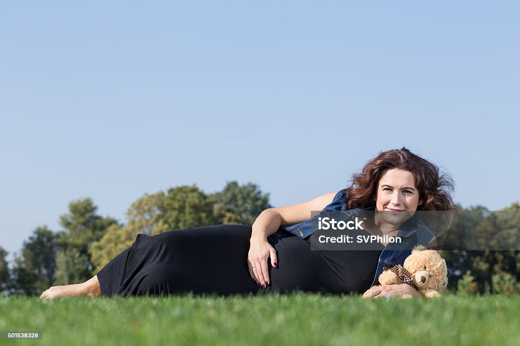 Pregnant woman is lying on the green lawn. Pregnant woman is lying on the green lawn. She is enjoying sunny day in the park. 2015 Stock Photo