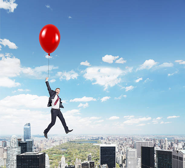 istock man flying with balloon over city 501539978