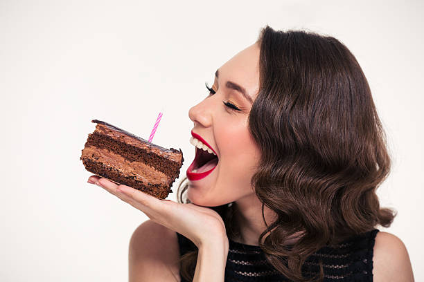 Positif belle femme mord morceau de gâteau d'anniversaire au chocolat - Photo