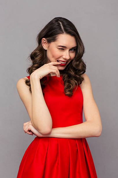 istock Woman in red dress winking at camera 501542376