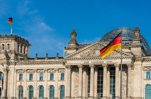 Bundestag, Parliament of Federal Republic of Germany, with waving German and EU flags. Image taken with Nikon D800 and 16-35mm pro lens, developed and processed from RAW and distributed in XXXL size. Location: Bundestag, Berlin, Germany