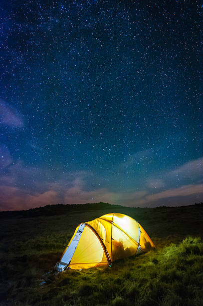 istock Stars shining over warmly glowing tent camping high on mountain 501547164