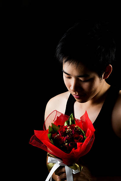istock Asian boy with red bouquet in dark background 501547881