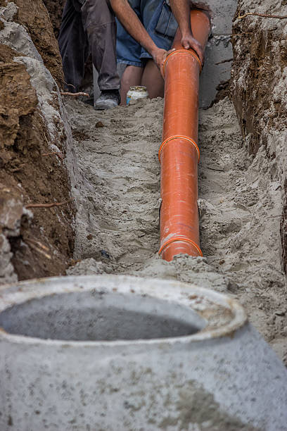 istock Workers laying PVC pipes at the ditch bottom 501548009