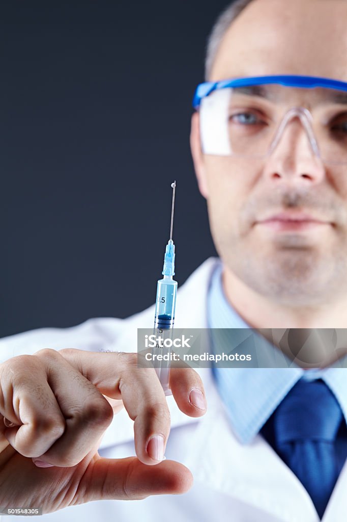 Scientist with syringe Doctor in protective glasses holding a syringe ready to inject 30-39 Years Stock Photo