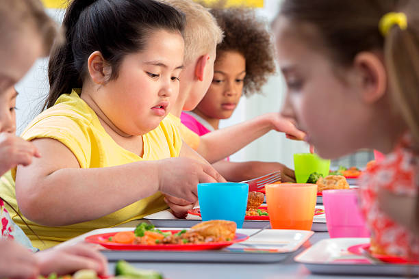 Children Eating School Dinners School children enjoying their school dinners overweight child stock pictures, royalty-free photos & images