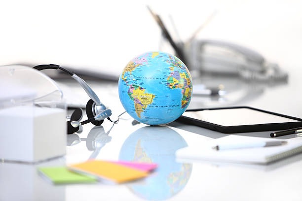 istock office desk with tablet, headphones, and globe 501552037