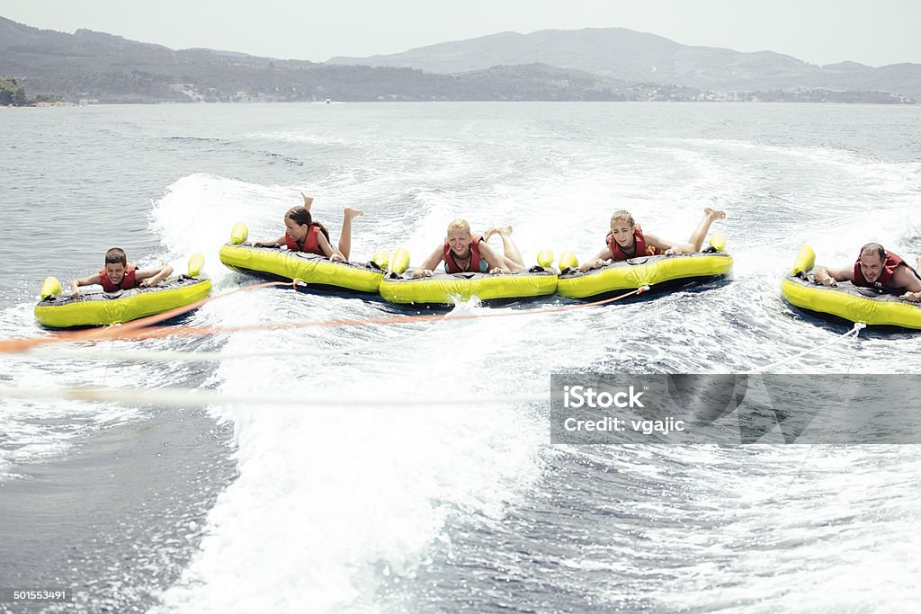 Happy People Enjoy Water Sports. Group of adults and children enjoy water sports, tubing on Greece, Halkidiki coastline. Action shot. Child Stock Photo
