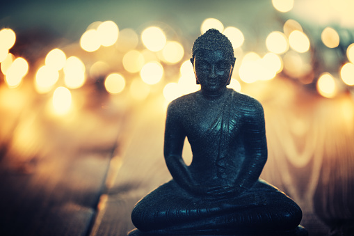 Buddha statue on blurred lights background. Shallow DOF - focus on the face