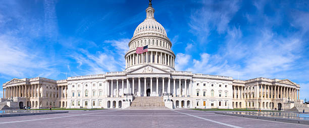 united states capitol mit flagge fliegen unter blauem himmel - hauptstadt stock-fotos und bilder