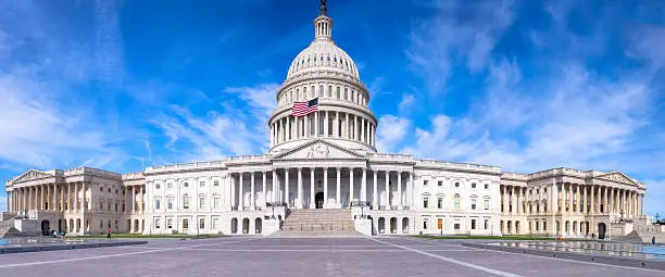 Photo of United States Capitol with Flag Flying under Blue Sky