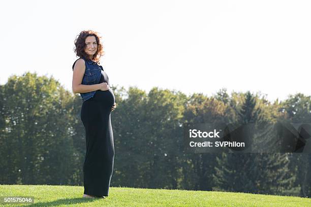 Pregnant Woman Is Standing On The Green Lawn Stock Photo - Download Image Now - 2015, Adult, Adults Only