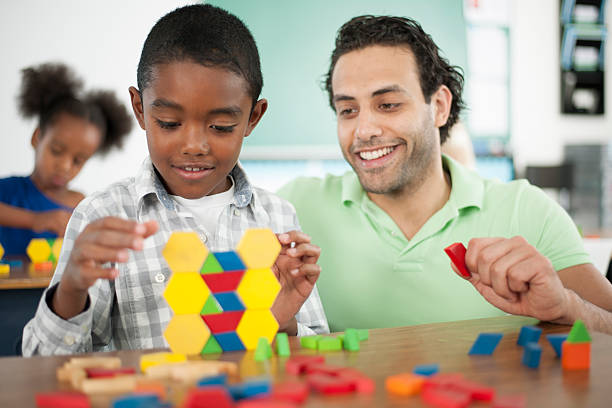 Creative Projects at School A teacher is helping a student with stacking blocks in class. math teacher stock pictures, royalty-free photos & images