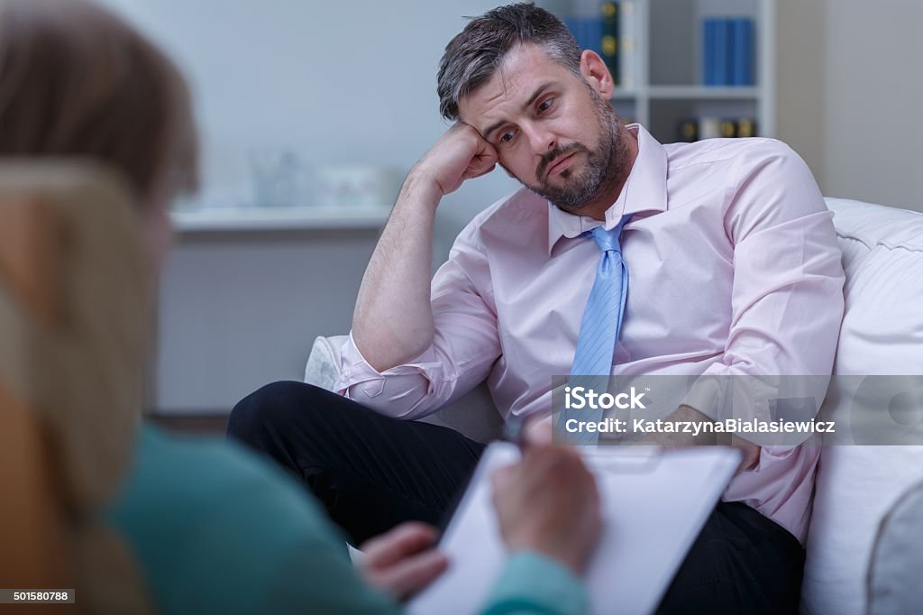 Despair businessman during psychotherapy Picture of despair young businessman during psychotherapy session 2015 Stock Photo