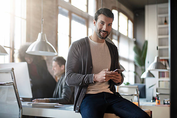 istock Businessman smiling with mobile phone sitting on his desk 501581538