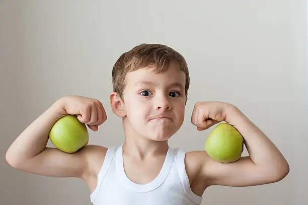 boy with green apples showing biceps face