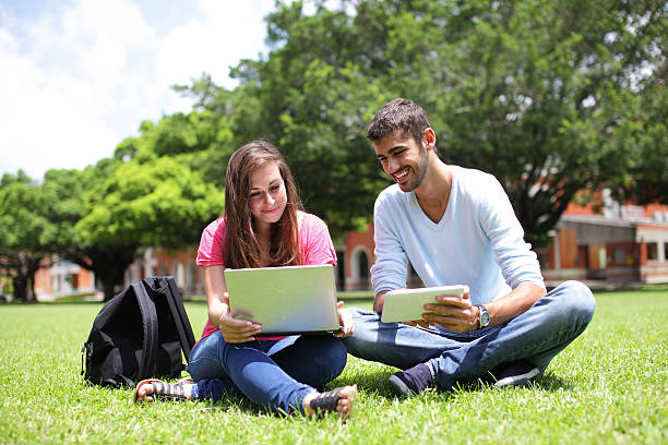 Happy College students using computer Happy College students using laptop and tablet pc on campus lawn, caucasian education student mobile phone university stock pictures, royalty-free photos & images