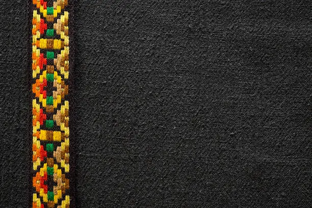 A close up of a piece of black fabric with a Native American Indian or bohemian style headband trim piece.