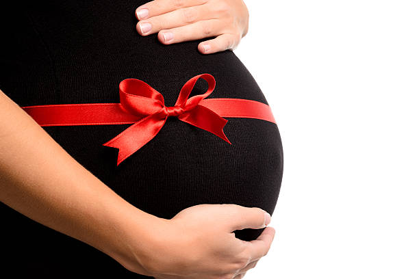 Pregnant is hugging belly with red satin ribbon Closeup pregnant woman is hugging belly with red satin ribbon stomach knot stock pictures, royalty-free photos & images