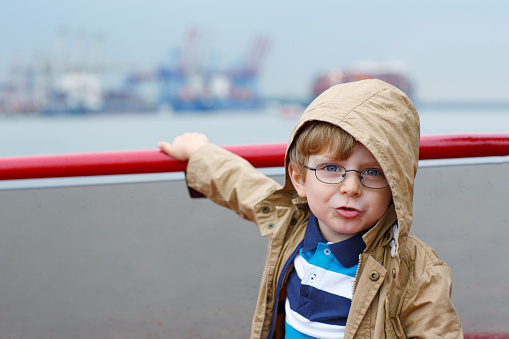 Little boy watching ships on a ferry.