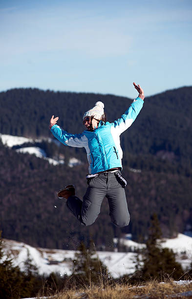 istock girl jumping in wintertime. Mountain background 501616378