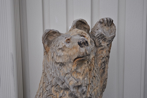 Wooden bear sculpture waving hello or goodbye. Chainsaw art.